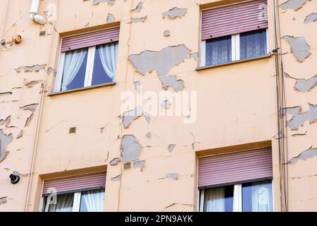 Abgelöste Farbe einer Wand eines Wohnungsgebäudes mit Fenstern Stockfoto