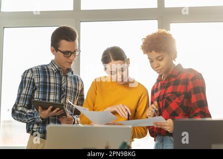 Teamwork Brainstorming Konzept für junge professionelle Teams. Fröhliche, ethnische Kollegen, die bei einer Bürobesprechung zusammenarbeiten. Verschiedene Kollegen diskutieren Projektideen und bearbeiten die Dokumentation Stockfoto