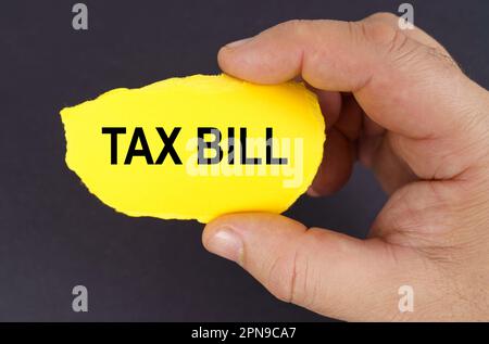 Geschäftskonzept. Auf schwarzem Hintergrund, in den Händen eines Mannes, ein gelber zerrissener Karton mit der Inschrift - Steuerrechnung Stockfoto
