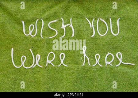 Ich wünschte, Sie wären hier in weißer Schrift auf einem grünen Kunstrasen-Hintergrund in albufeira algarve portugal Stockfoto