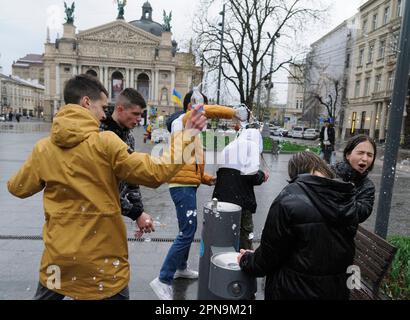Lemberg, Ukraine. 17. April 2023. Die Ukrainer gießen sich auf der Straße im Stadtzentrum inmitten der russischen Invasion in die Ukraine gegenseitig Wasser. Der Brauch des Wassertauchens ist ein uralter Ritus der Frühjahrspülung, der am Ostermontag stattfindet. Kredit: SOPA Images Limited/Alamy Live News Stockfoto
