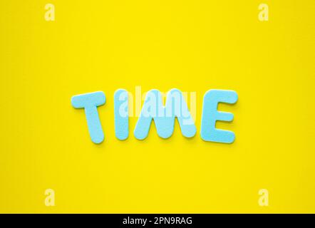 ZEITTEXT mit blauen Buchstaben auf gelbem Hintergrund, Geschäftskonzept mit Kopierbereich. Zeitkonzept. Nahaufnahme des Kopierplatzes, Zeitmanagement. Stockfoto