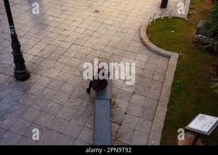 Draufsicht einer älteren Frau, die auf der Bank in Palermo sitzt. Stockfoto