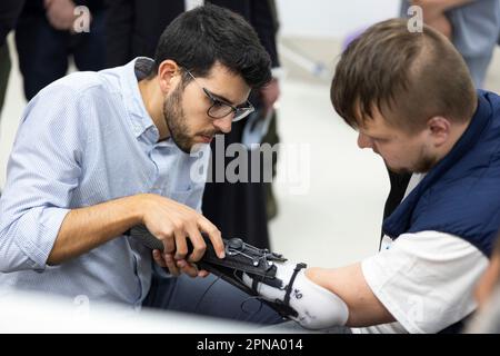 Wynnyky, Ukraine. 14. April 2023. Open Bionics Helder Goncalves, Left, justiert eine fortgeschrittene Prothese für einen verwundeten Veteran während der Einweihung des Superhumans Prothetik- und Rehabilitationsmedizinischen Zentrums, 14. April 2023 in Lemberg, Ukraine. Kredit: Ukrainischer Ratsvorsitz/Pressestelle Des Ukrainischen Präsidenten/Alamy Live News Stockfoto