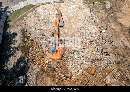 Luftaufnahme des Abbruchgeländes. Bagger in den Ruinen eines abgerissenen Gebäudes. Stockfoto