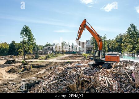 Bagger auf einem Stapel von Abfällen aus einem zerlegten Gebäude an einer Abbruchstelle. Drohnenfoto. Stockfoto