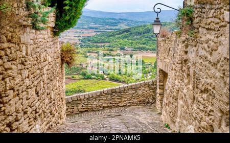 Das mittelalterliche Dorf Gordes in der Region Luberon der Provence, Frankreich, mit Blick auf ein breites Tal mit Kulturfeldern, Obstgärten und Weinbergen Stockfoto