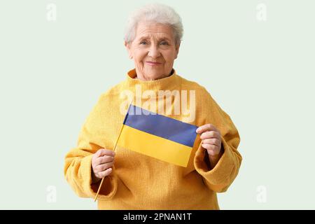 Seniorin mit ukrainischer Flagge auf grünem Hintergrund Stockfoto