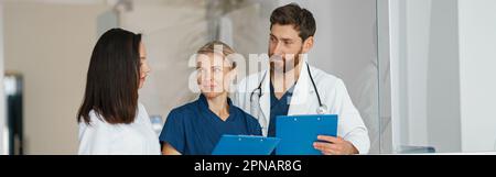 Eine Gruppe von Kollegen aus dem Arzt, die die Patientendiagnose besprechen, steht in der Klinikhalle Stockfoto