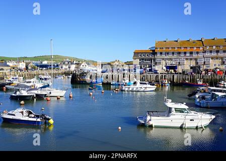 Fischerboote im Hafen mit Wohnungen und Stadtgebäuden im hinteren Teil, West Bay, Dorset, Großbritannien, Europa. Stockfoto