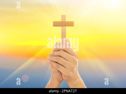 Menschliche Hände hielten ein Kreuz heilig und beteten um Segen von Gott. Amour Anbetung Gott Konzept. Stockfoto