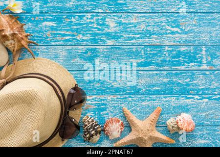 Hut, Sonnenbrille, Plumeria und Muschel. Auf Holzbrett. Sommerferienkonzept. Stockfoto