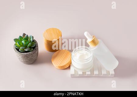 Verjüngungscreme und Serum zur Gesichts- und Körperhautpflege in Kosmetikbehältern auf pastellfarbenem Hintergrund. Natürliche Kosmetik Stockfoto