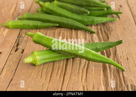 Okra, Lady's Finger, Bhindi und Bamies, Gemüse und Kräuter auf einem Holztisch. Stockfoto