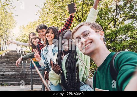 Eine vielfältige Gruppe von Freunden der Generation Z, darunter eine Engländerin, Italiener, eine Filipino und ein afrikanisches Mädchen mit Dreadlocks, die glücklich zusammen für ein Selfie posieren Stockfoto