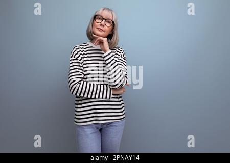 Eine gut gepflegte Frau mittleren Alters in einem modischen Bild flirtet auf einem hellen Studiohintergrund Stockfoto