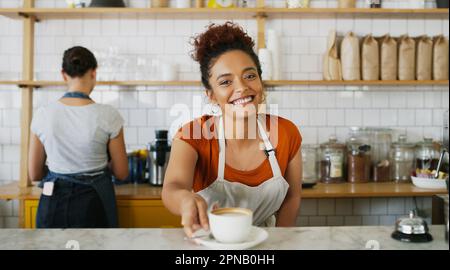 Wenn Sie fertig sind, sollten Sie um eine zweite Tasse bitten. Porträt einer jungen Kellnerin, die eine Tasse Kaffee in einem Café serviert. Stockfoto