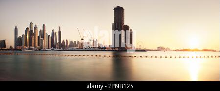 Dubai, 13. Januar 2023: Moderne Gebäude mit goldenen Reflexionen des Sonnenuntergangs auf der Dubai Marina Bay mit Blick von Palm Jumeirah, Vereinigte Arabische Emirate. Stockfoto