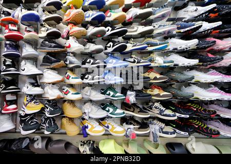 Schau dir viele Sportschuhe an der Wand an. Ein Blick auf eine Schuhwand im Geschäft. Moderne, neue, stylische Laufschuhe für Sneaker. GE Chi Minh C. Stockfoto