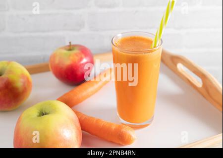 Frisch gepresster Karotten-Apfelsaft in einem Glas mit Trinkhalm Stockfoto