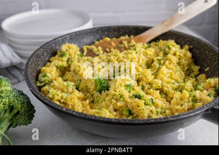 Gesunde glutenfreie Beilage mit braunem Reis. Gekocht mit Brühe, Currypulver und Brokkolisprossen. Stockfoto