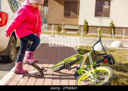 Ein kleines Mädchen pumpt einen Fahrradreifen hoch Stockfoto