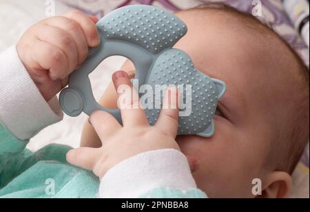 Ein kleiner Junge spielt mit einem Beißring während des Ausbruchs der ersten Zähne. Juckreiz und Zahnfleischschmerzen am ersten Zahn. Stockfoto