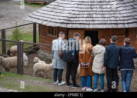 Lemberg, Ukraine. 17. April 2023. Erwachsene und Kinder stehen in der Nähe eines Gehäuses mit Schafen Trotz des Krieges feiern die Menschen den zweiten Ostertag und besuchen den Park mit Vieh, um sie zu füttern, Spaß zu haben und Zeit mit Familienkredit zu verbringen: SOPA Images Limited/Alamy Live News Stockfoto