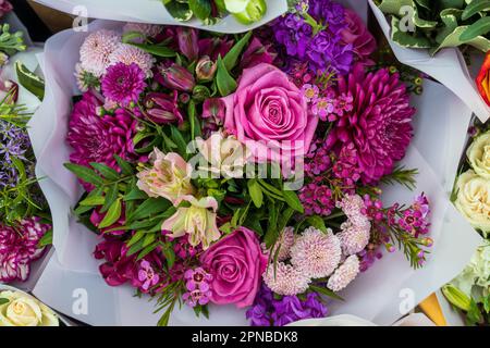 Rosa, rote und orangefarbene Chrysanthemen, Lisianthus und Gerbera mit grünem Eukalyptus in einem roten Strauß Stockfoto