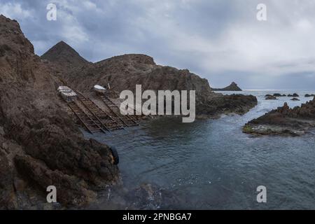 Spektakuläre Landschaft von Cabo de Gata in den Felsformationen des Almeria-Riffs mit hölzernen Ständen zwischen den Bergen für die Sicherheit der Boote bei Stürmen Stockfoto
