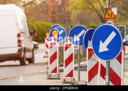 Obligatorische Straßenschilder für die Umleitung von Hindernissen links und Sicherheitsschilder auf der Straße, die gewartet und repariert wird, selektiver Fokus Stockfoto