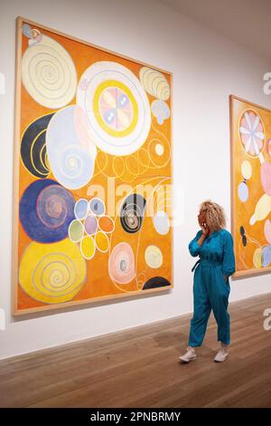 London, Großbritannien. 18. April 2023. Tate Modern präsentiert eine Ausstellung von Hilma af Klint und Piet Mondrian, zwei Pionieren der abstrakten Kunst mit sehr unterschiedlichen Empfindlichkeiten. Hier sieht eine Frau ein Werk, „No. 3, Youth“ aus Hilma af Klints Serie The Ten Largest, Group IV aus dem Jahr 1907. Kredit: Anna Watson/Alamy Live News Stockfoto