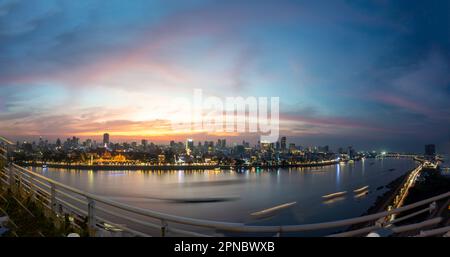 Das goldene Nachglühen über Kambodschas Hauptstadt, das geschäftige Flussufer und berühmte Wahrzeichen und der Königspalast, während die untergehende Sonne von hinten sinkt Stockfoto