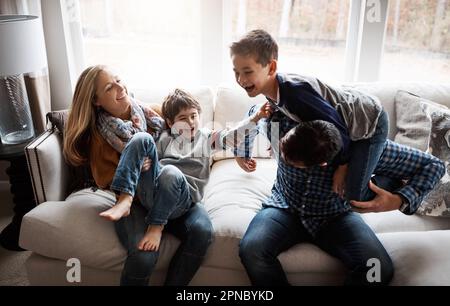 Eine gute Zeit stärkt die Bindung der Familie. Zwei süße kleine Jungs, die sich mit ihren Eltern zu Hause amüsieren. Stockfoto