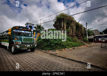 Ein neu lackierter Schulbus parkt vor dem Atrium der Kolonialkirche von Guaymango, El Salvador, America Cemtrale Stockfoto