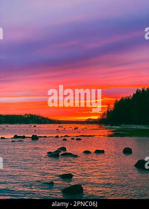 Wunderschöner heller, farbenfroher Sonnenuntergang über der Meeresbucht bei Ebbe Stockfoto