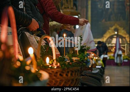 LEMBERG, UKRAINE - 15. APRIL 2023 - Gläubige organisieren ihre Osterkörbe, um am Heiligen Peter und Paul Garrison Kirche am Heiligen Samstag, Lemberg, Stockfoto