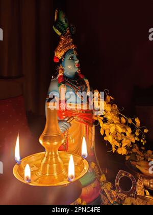 Beleuchtete Messingöllampe - Nilavilakku/Blaues Idol von Lord Krishna/Cassia-Fistel/Goldene Duschblumen/Vishu kani/Vishu Festival/Kerala Stockfoto