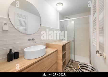 Gemütliches Bad mit Spiegelwaschbecken und Schränken im Hintergrund einer Dusche in einem renovierten Apartment. Das Konzept eines geräumigen Badezimmers für ein großes Stockfoto