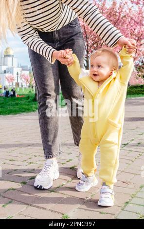 Die ersten Schritte des Babys mit der Hilfe der liebevollen Mutter Stockfoto