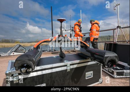 Aseleben, Deutschland. 18. April 2023. Eine schwimmende Sonobot-Drohne steht auf einer Box. Die schwimmende Drohne kann den Grund des Sees mit Sonar unabhängig voneinander scannen und anzeigen. Diese moderne Technologie wird zum ersten Mal bei der Suche nach archäologischen Schätzen unter Wasser auf dem Grund des Lake Suess eingesetzt. Kredit: Heiko Rebsch/dpa/Alamy Live News Stockfoto