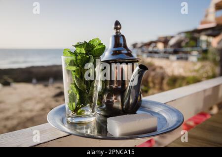 Traditionelle marokkanische Teekanne mit einer Tasse im Freien, trinkfertig Stockfoto