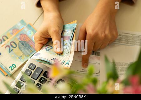Die Hände einer jungen Frau mit Banknoten, die Geldzählung, die Zusammenfassung der Kosten für das Trimester, die Heizperiode, den Anstieg der Preise für Versorgungsleistungen Stockfoto