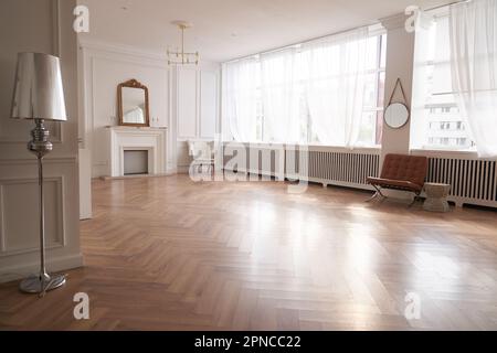 Helle Einrichtung mit großen Fenstern und einem Kamin im klassischen Stil. Großes Wohnzimmer mit Dekorartikeln. Wunderschönes Parkett und Kopierraum. Hochwertiges Foto Stockfoto