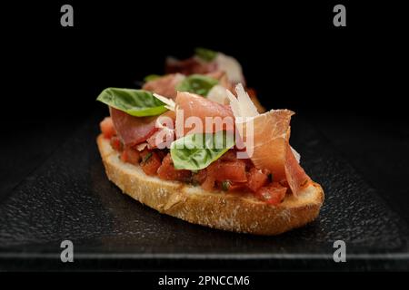 Köstliches Bruschetta garniert mit geräuchertem Lachs, Schinken und Parmesan Stockfoto