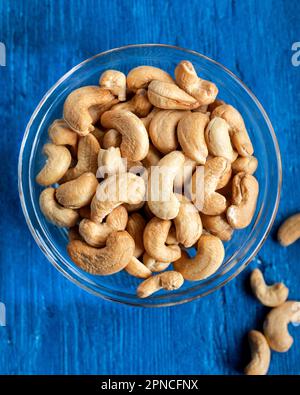 Leckere Kaschu-Nüsse in einer Schüssel auf einem Holztisch, Blick von oben. Schale mit Kaschu-Nüssen auf einem Holztisch, flach liegend. Stockfoto