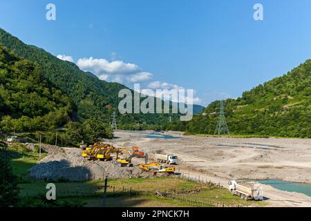 Durch das Räumen des Flussbetts in den Bergen, Baumaschinen, Bagger und Lastwagen werden die Folgen der Frühjahrsflutungen von Bergflüssen beseitigt. Stockfoto