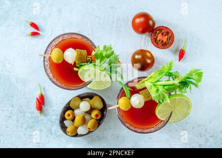 Bloody Mary Cocktail mit Garnierung, über Kopf flach liegender Schuss. Scharfer Tomatensaft mit Alkohol, Limette, Gurken, Sellerie und Paprika Stockfoto