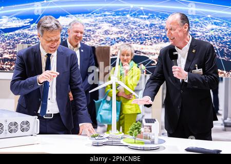 Hannover, Deutschland. 18. April 2023. Robert Habeck (Bündnis 90/die Grünen, l), Bundesminister für Wirtschaft und Klimaschutz, steht vor einem Modell einer Windturbine während einer Führung durch den Stand von Phoenix Contact auf der Hannover Messe. Daneben stehen die Mitarbeiter Klaus Hengsbach (2. von links), Angela Josephs (M) und Frank Stührenberg (r), CEO Phoenix Contact. Vom 17. Bis 21. April 2023 findet die weltweit größte Industriemesse statt. Kredit: Michael Matthey/dpa/Alamy Live News Stockfoto