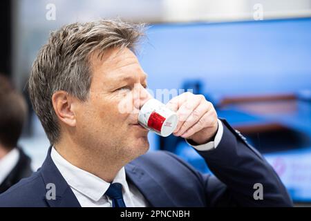 Hannover, Deutschland. 18. April 2023. Robert Habeck (Bündnis 90/die Grünen), Bundesminister für Wirtschaft und Klimaschutz, steht am Stand der HAWE Hydraulik während einer Führung durch die Hannover Messe und Getränke aus einem Espresso-Becher. Vom 17. Bis 21. April 2023 findet die weltweit größte Industriemesse statt. Kredit: Michael Matthey/dpa/Alamy Live News Stockfoto